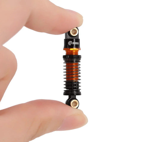 Close-up of 45mm Aluminum Threaded Oil Shock Absorber for One Twenty Fourth FCX24 and FMS RC Cars held between fingers.