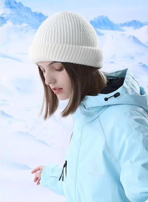 Person wearing a white beanie and blue winter jacket in snowy surroundings