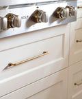 Set Of 12 SleekTouch Antique Brass Cabinet Pulls, 3 3/4 Inch Center To Center installed on white kitchen drawers near stove