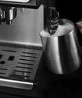 Stainless Steel Milk Frothing Pitcher 12 Oz For Espresso Machines, Perfect For Cappuccino And Latte Art, shown beside machine
