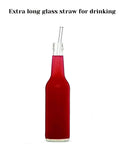 Glass bottle with red liquid and extra-long glass straw