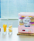 Smooth Operator Electric Food Dehydrator Machine With Five Adjustable Trays And Digital Timer in pink, with dehydrated fruits displayed.