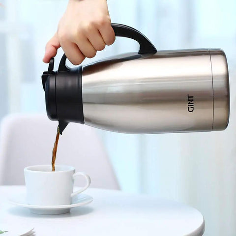 Stainless Steel Thermal Coffee Carafe With Double Wall Vacuum Insulation Keeps Your Brew Piping Hot Up To 12 Hours Or Cold Up To 24 Hours 65 Oz One Point Nine Liter Leak Proof Lid Silver being poured into a cup on a table.
