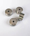 Four metal poppet seats for water jet cutting machines, round discs with center holes.