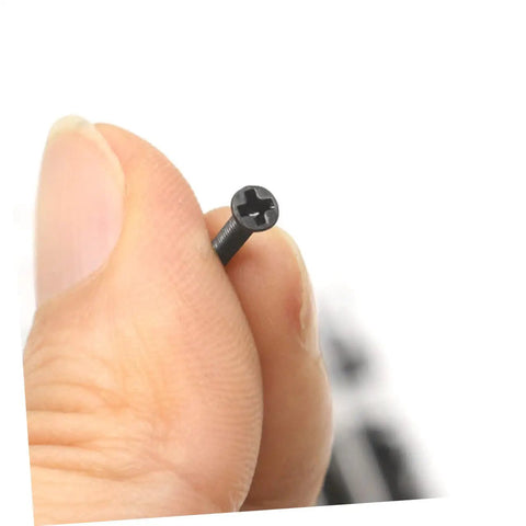 Close-up of a hand holding a screw from the 18 Piece Miniature Screw Set With Flat Countersunk Head Micro Screws For Glasses, Watches, And DIY Projects In A Clear Storage Box Ideal For Pros And DIYers Who Need Tiny Screws On Hand.