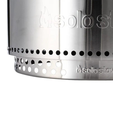 Close-up of Yukon 27 Inch Stainless Steel Fire Pit showing vent holes and logo engraving on metallic surface.