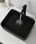 Black rectangular vessel sink with running water on marble counter