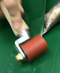 Close-up of red 40mm silicone seam roller with brass detail on green roofing membrane