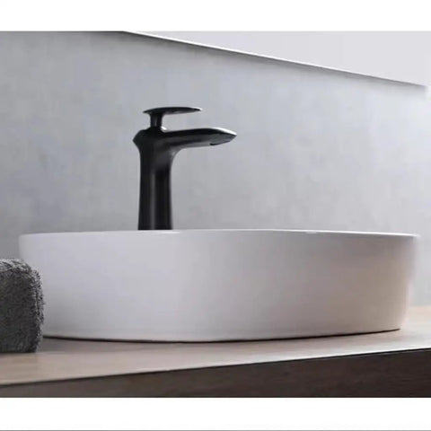 USZWBY Vessel Sinks Minimalist Ceramic Table Basin Home Hotel Bathroom Washbasin with sleek black faucet on wooden surface.