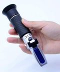 Hand holding Dual Scale Brix Refractometer With ATC For Specific Gravity And Brix Readings Hydrometer Kit For Wine Making Beer Brewing And Homebrew DIYers For Serious Hobbyists And Pros Alike