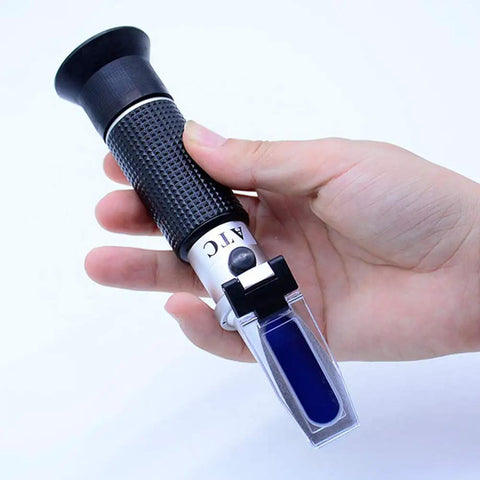 Hand holding Dual Scale Brix Refractometer With ATC For Specific Gravity And Brix Readings Hydrometer Kit For Wine Making Beer Brewing And Homebrew DIYers For Serious Hobbyists And Pros Alike