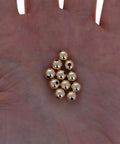 Straight Premium 6MM Gold Filled Round Beads For Jewelry Crafting, smooth round gold beads held in a palm, seamless design.