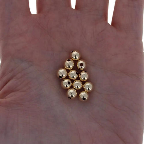 Straight Premium 6MM Gold Filled Round Beads For Jewelry Crafting, smooth round gold beads held in a palm, seamless design.