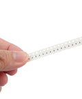 SMD resistor strip on white carrier tape (1206 size) held by fingers.
