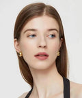 Half Ball Stud Earrings for Women, Gold Tone 20mm Round Ball Jewelry, Minimalist Yet Bold Everyday Earrings, Lightweight 3.2g, Gold Plated Stainless Steel, Lead Free, the Perfect Accessory That Goes With Any Fit. Model wearing gold half-ball stud earrings on white background