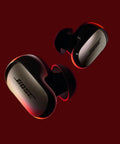 QuietComfort Ultra Earbuds 2nd Gen Dope Wireless Noise Canceling With Built In Microphone Immersive Audio USB C Charging Up To Six Hours Battery Life IPX4 Rating Black, shown on a maroon background.
