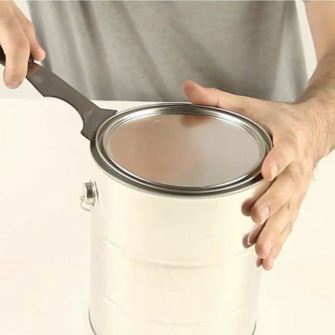 Using Six In One Painter Tool For DIYers With Scraper, Putty Knife, Roller Cleaner, Nail Setter, Gouger And Spreader on a paint can