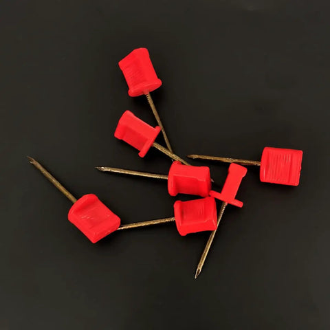 Close-up of 20Pack Archery Target Pins Heavy Duty Manganese Steel Nails with plastic heads, showing red pins on black background.