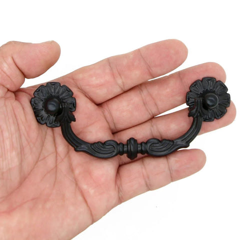 Hand holding a Six Pcs Vintage Black Drawer Pulls Handles Metal Bail Pulls for Cabinets in classic antique style, shown in detail.