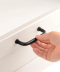 Hand holding Five Pack Matte Black Modern Cabinet Pulls 3.75 Inch Hole Center 96mm Dresser Drawer Handles on white cupboard