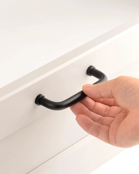 Hand holding Five Pack Matte Black Modern Cabinet Pulls 3.75 Inch Hole Center 96mm Dresser Drawer Handles on white cupboard