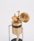Close-up of Retro Three Legged Oscillating Steam Engine Model Kit For Hands On STEM Fun, brass gear meshing and piston action.
