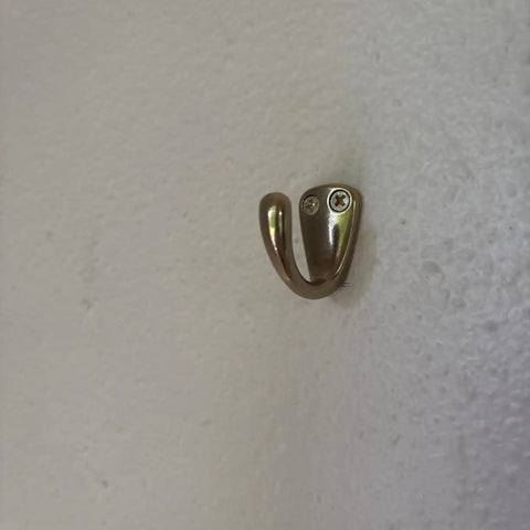 Small Solid Brass Wall Mounted Hanging Hooks Duo Pack Slick Dope Gold Finish showing a single hook on a white wall.