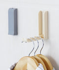 Slick Foldable Wall Hooks With Adhesive Backing For Space Saving No Drill Setup To Hang Jackets Purses Hats Or Dog Leashes In Foyer Closet Easy Install Design Works As A Lifesaver To Keep Home Clutter Free Always Two Pack gray and beige hooks with wooden hangers.