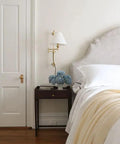 Classic Swing Arm Wall Sconce Featuring Distressed Bronze Finish One Light Adjustable Vanity Lamp 10 By 29 Inches Rustic Home Decor Absolutely Gotta Get beside a bed with flowers on a nightstand.
