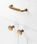 Ten Pack Antique Brass Cabinet Pulls With Three And Three Quarters Inch Hole Centers for cabinets, shown on white cabinet.