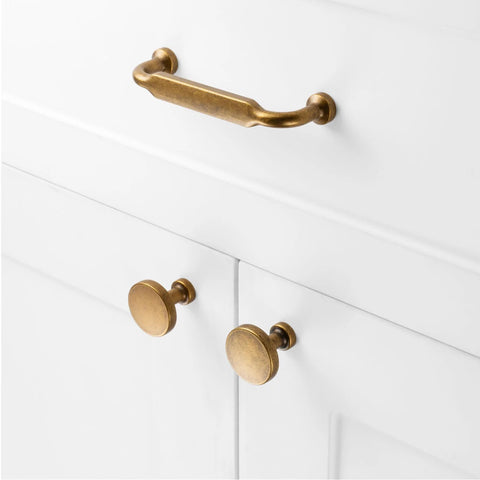 Ten Pack Antique Brass Cabinet Pulls With Three And Three Quarters Inch Hole Centers for cabinets, shown on white cabinet.