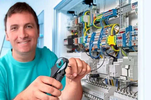 Electrician working on circuit panel with tools in hand.