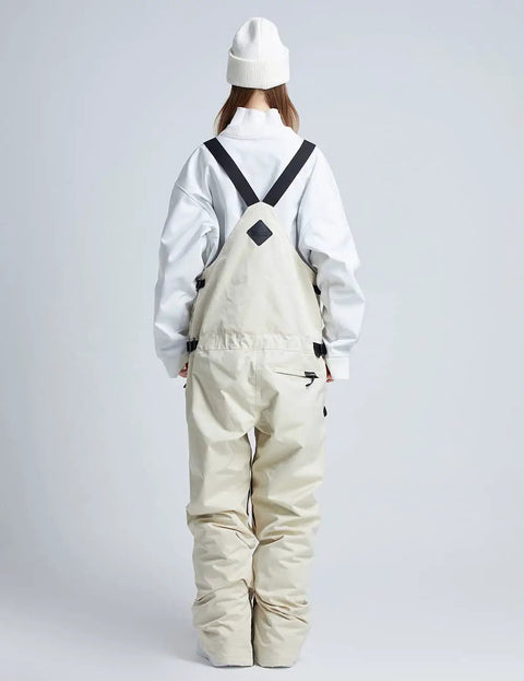 Rear view of khaki Unisex Ski Bibs Waterproof Snow Overalls Warm Insulated Windproof Snowboarding Pants worn by person in white beanie.