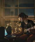 Musician using laptop with 104-BT Compact Desktop Studio Monitors With Bluetooth, Black Finish, pair of 4.5-inch speakers
