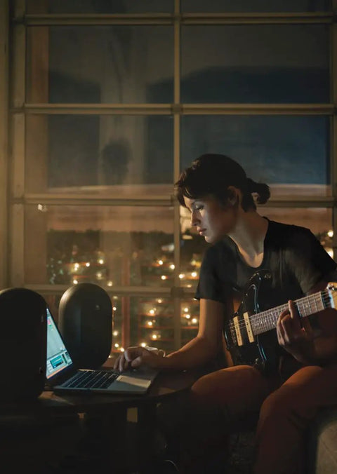 Musician using laptop with 104-BT Compact Desktop Studio Monitors With Bluetooth, Black Finish, pair of 4.5-inch speakers