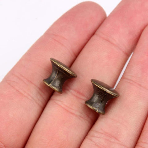 Close-up of two 10 Pcs Vintage Bronze Drawer Pull Handles Zinc Alloy Mini Metal Knobs held in hand for size reference.