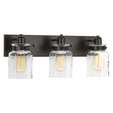 Calhoun Collection Clear Glass Farmhouse Bath Vanity Light Three Light Antique Bronze Finish With Thick Glass Shades Front View