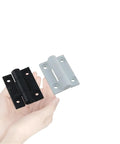 Two damping hinges in black and white finishes held in hand; metal hardware for industrial equipment