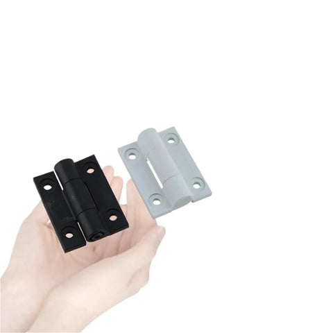 Two damping hinges in black and white finishes held in hand; metal hardware for industrial equipment