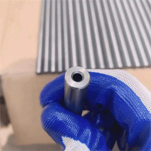 Close-up of a silver 22mm chromoly steel hydraulic tube end, seamless hollow cylinder held by a blue glove.