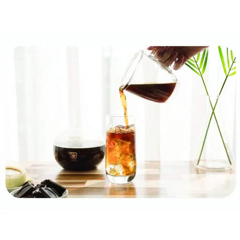 Heavy Duty Dutch Cold Brew Coffee Maker With Solid Wood Tower And Stainless Steel Filter brewing iced coffee into a glass.