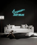 Just Relax LED Neon Light Sign For Wall Decor USB Powered With Switch Bright Neon Lights above a white couch in a dark room.
