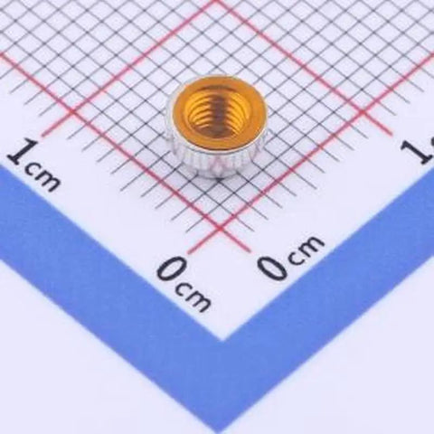 20 Pack SMD Surface Mount Round Nuts Circuit Board Hardware M3x1.5 Copper Tinned Columns on grid paper for electronics assembly.