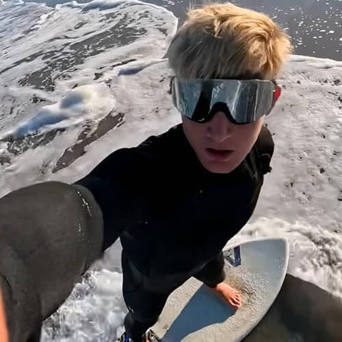 Person surfing wearing Frameless Ultralight Black Mirror Swim Goggles With VisiClear Nanotech Anti Fog Lens And 100 Percent UV Protection