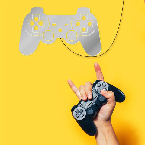 Person holding a black controller under a silver Gamer Neon Sign With 7 Color Changing Mirror LED Backlight Design Luminous Wall Sign For Game Room Decor Cool Teen Bedroom Wall Lamp And Video Game Decor on yellow wall.
