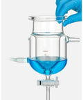 Close-up of 100ml clear glass vessel with blue liquid, showing PTFE diverter valve for Heavy Duty Three Port Double Jacketed Open Reactor.