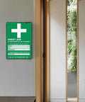 Durable Aluminum First Aid Location Sign 12 By 8 Inches With Ultra Readable Crisp Printing on a hallway wall.