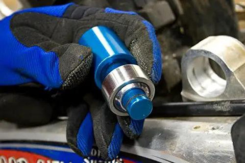 Shop Grade Blue Ktm Heim Joint Tool With Comfort Grip For Heavy Dirt Bike Suspension Work And Quad Repairs Features Locking O Ring Mechanism For Fast Seal Alignment And Solid Bearing Installations held in a gloved hand.