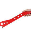 Person holding red wood push stick with ergonomic handle design for safer woodworking on table saws, shapers, jointer, and router tables.