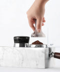 Top Shelf Marble Espresso Tamper Holder Stand Fits 51mm And 54mm Coffee Tools in use with coffee grounds on a kitchen counter.